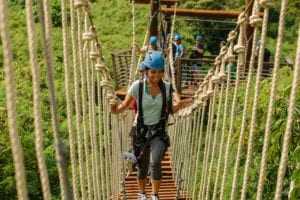 A woman crossing a rope bridge at CLIMB Works Keana Farms.