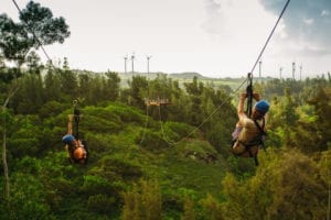 Happy zipliners soaring through the mountains at CLIMB Works Keana Farms.