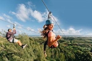 friends ziplining in oahu side by side